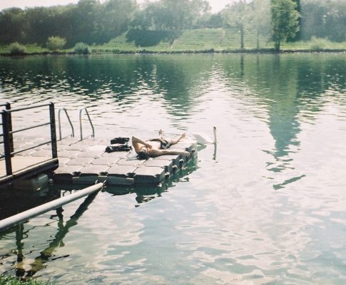 One lying in the sun, one gliding on the water